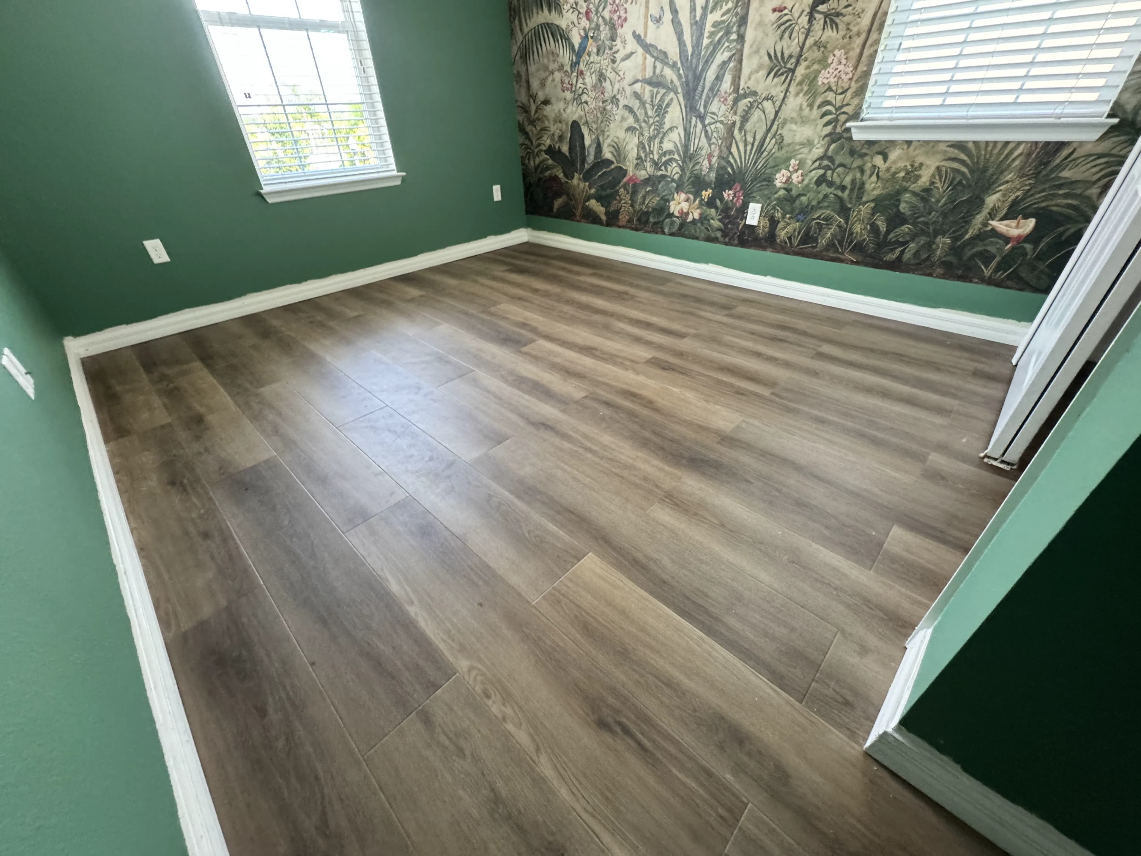 Wood-look flooring in a green room with a botanical accent wall